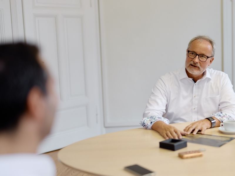 GFA FP_Strategien Ein Mann sitzt am Tisch und spricht. Vor ihm liegen einige Edelmetalle.