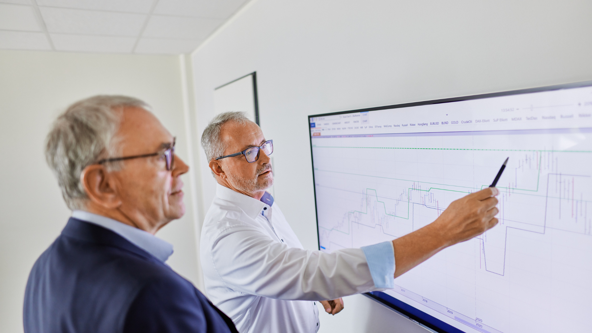 Das Foto zeigt zwei Männer, die einen Aktienchart analysieren.