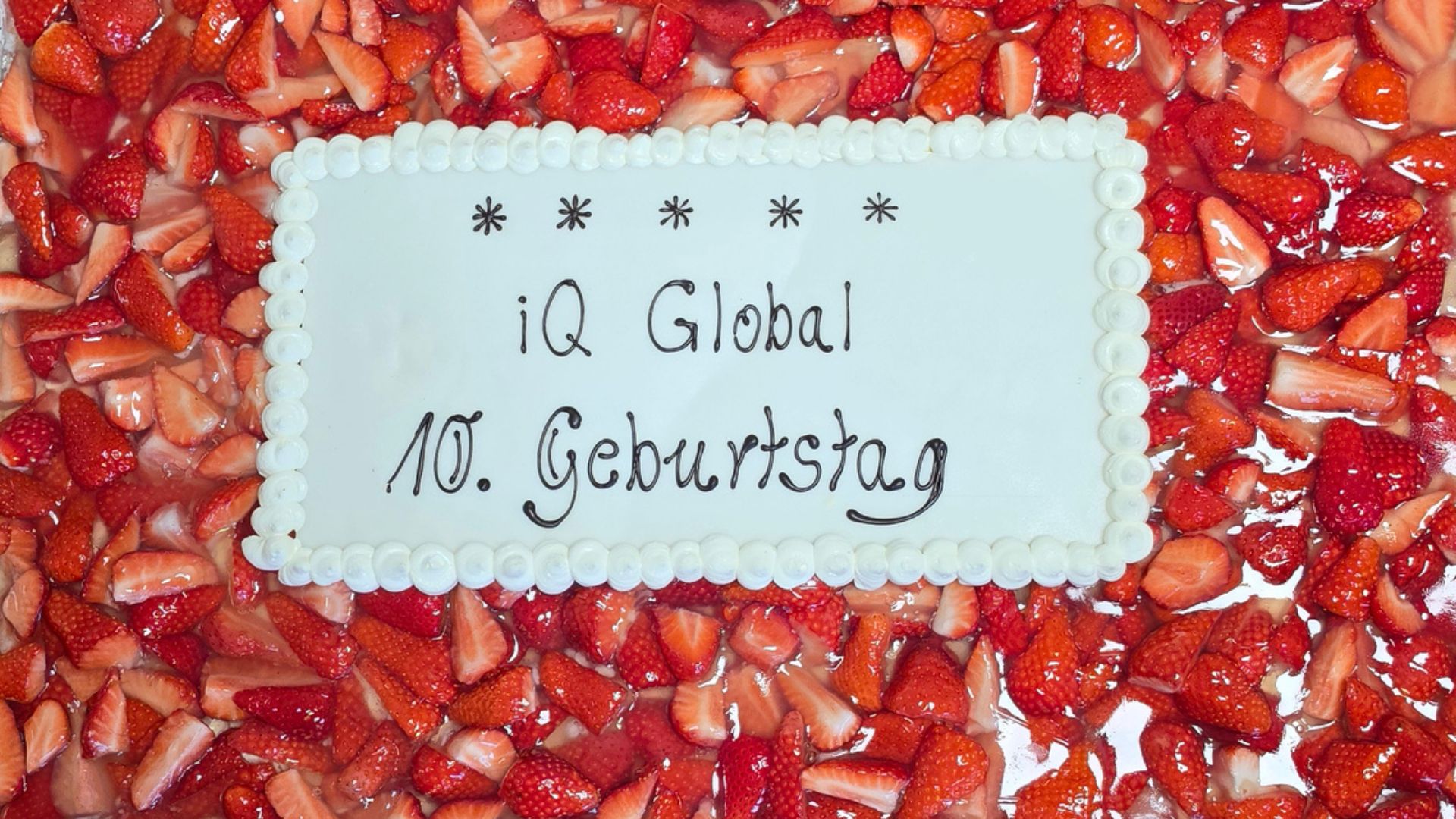 Das Foto zeigt einen Erdbeerkuchen mit Aufschrift "iQ Global 10. Geburtstag"